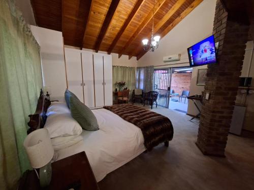 a bedroom with a large bed with a television in it at De Windmolen in Centurion