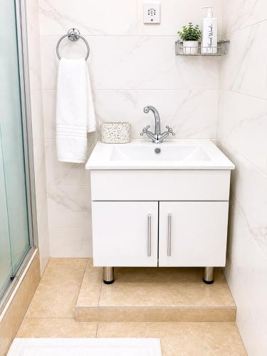 a white bathroom with a sink and a mirror at Wilo Residence in Victoria Falls