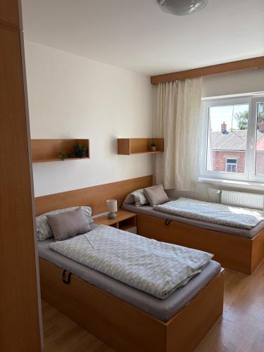 two beds in a room with a window at Penzion U Tomáše in Ratíškovice