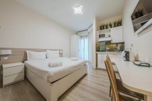 a white bedroom with a bed and a kitchen at Cristel Apartment - 15 min da Milano in Cormano