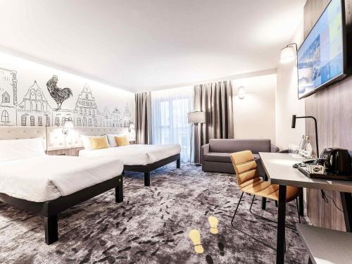 a hotel room with two beds and a desk at ibis Styles Lublin Stare Miasto in Lublin