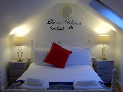 a bedroom with a white bed with a red pillow at 1844 Seascape Cottage in Fanore
