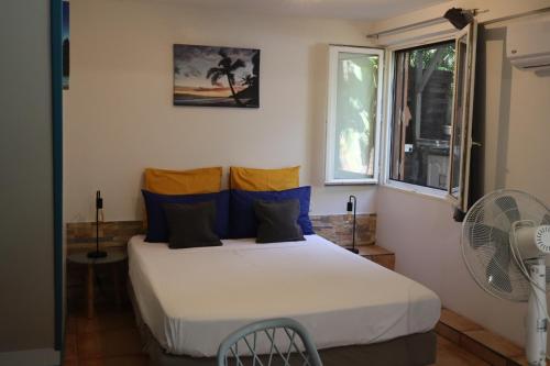 a bedroom with a bed with blue and yellow pillows at Ti Kaz Ravinala in Ravine des Cabris