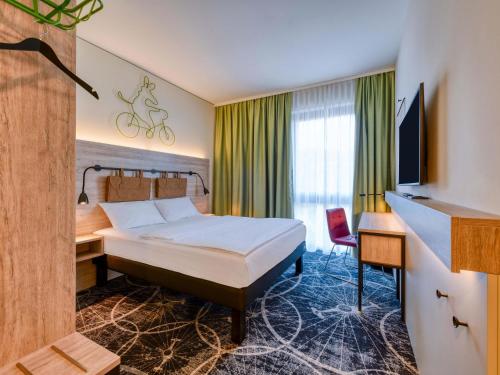 a hotel room with a bed and a desk at ibis Styles Magdeburg in Magdeburg