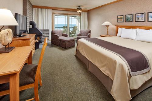Habitación de hotel con cama, escritorio y TV. en Cavalier Oceanfront Resort en San Simeon
