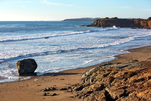 a sandy beach with a large rock in the ocean at Cavalier Oceanfront Resort in San Simeon