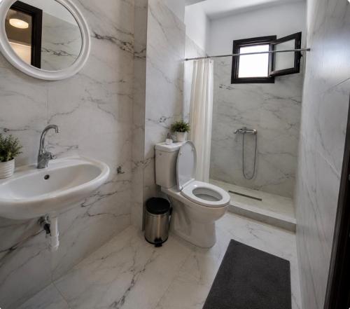 a white bathroom with a toilet and a sink at Basilio's Studios in Leptokarya