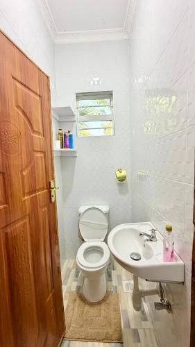 a white bathroom with a toilet and a sink at Serenity Elgon Stay in Eldoret
