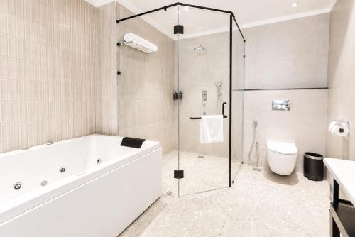 a bathroom with a shower and a tub and a toilet at White Wharf Manesar in Gurgaon
