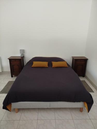 a bedroom with a black bed with yellow pillows at le chardonneret in Commer