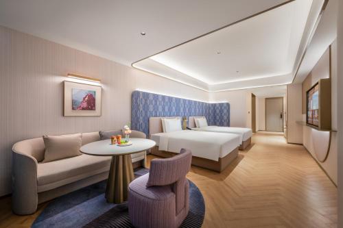a hotel room with a bed and a couch and a table at Manxin Hotel Xian Bell Tower in Xi'an