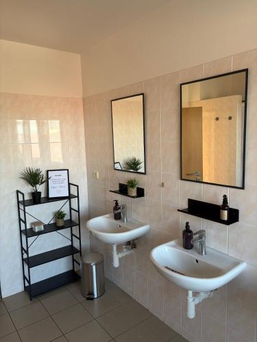 a bathroom with two sinks and two mirrors at Penzion U Tomáše in Ratíškovice