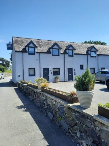 a white building with a stone wall in a parking lot at Rwst Holiday Lodges in Llanrwst