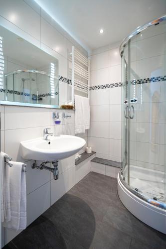 a white bathroom with a sink and a shower at Hotel Garni Ammergauer Hof in Oberammergau