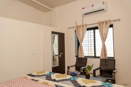 a bedroom with a bed and two chairs at Ananda Villa in Igatpuri