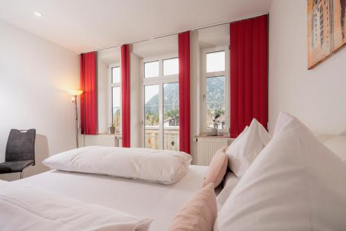a bedroom with two beds and red curtains at Hotel Garni Ammergauer Hof in Oberammergau