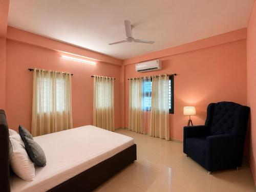a bedroom with a bed and a black chair at Villa by Stay Junction in Indore