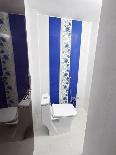 a bathroom with a toilet and a blue wall at Villa by Stay Junction in Indore