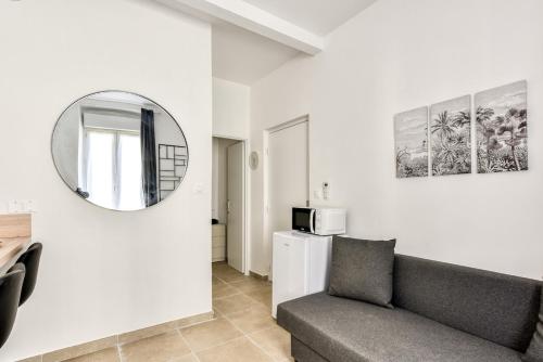a living room with a couch and a mirror at La Petite Maison - Studio in Peyriac-de-Mer
