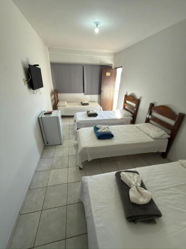 a hotel room with three beds and a tv at Hotel Tropical in Aquidauana