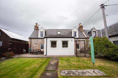 a house with a green flag in the yard at 3BR Cottage with Garden, Free Parking for 6 Guests in Alness