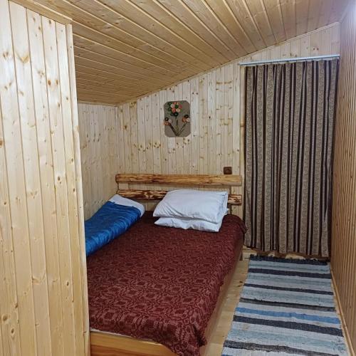 a small room with a bed in a wooden cabin at La tataie Nucșoara in Nucşoara