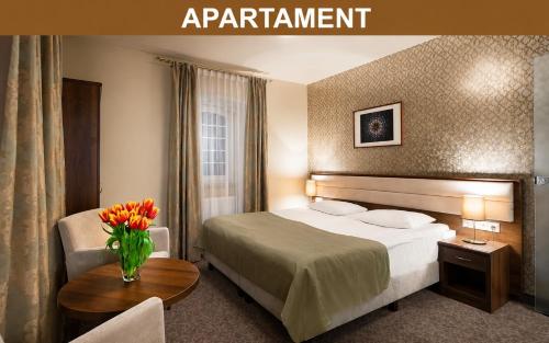 a hotel room with a bed and a vase of flowers at Hotel Miodowy Młyn in Opatów