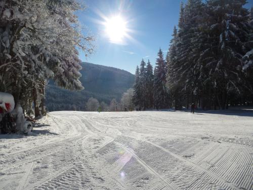 a snow covered ski slope with the sun in the sky at Ubytování Lyžařská škola in Kubova Huť