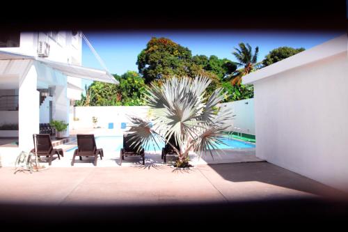 a patio with chairs and a palm tree next to a building at Hotel Anamela in Maní