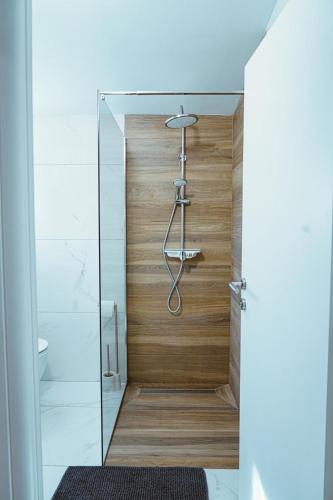 a shower with wooden walls and a glass door at Nada Apartment near Krka National Park in Skradin