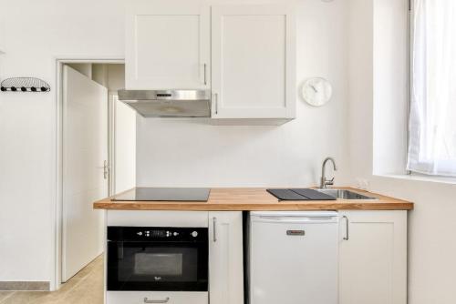 a kitchen with white cabinets and a sink at La Petite Maison - T1 Bis in Peyriac-de-Mer