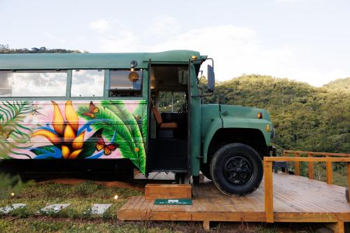 a green bus is parked on a wooden deck at D'Alma Bus com café da manhã in Pomerode