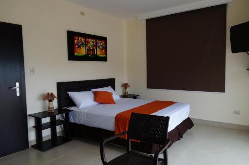 a bedroom with a bed and a chair and a large screen at Playa Aventura Hotel in Ayangue