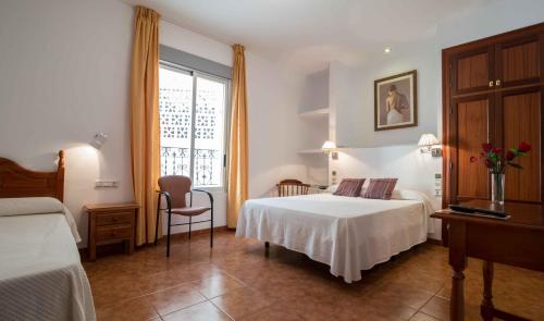 a hotel room with two beds and a window at Hotel Andalucia in Lanjarón
