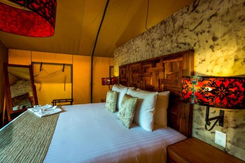 a bedroom with a bed and two lamps at Serenity Authentic Glamping Tulum in Xpu Ha