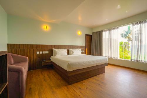 a bedroom with a bed and a chair in it at Tiger Hill Hotel & Suites in Kalpetta