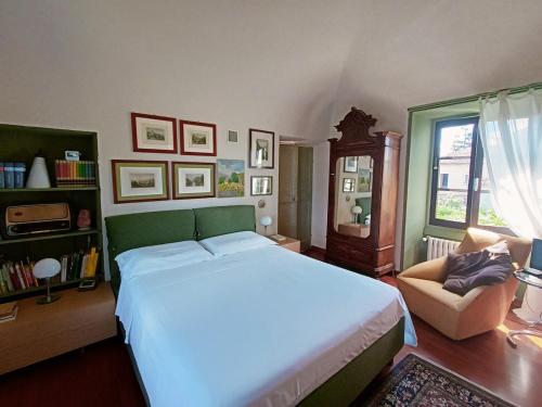a bedroom with a large white bed and a chair at La Canonica della Merella B&B in Novi Ligure