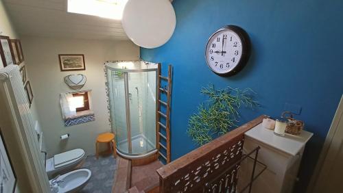 a bathroom with a clock on a blue wall at La Canonica della Merella B&B in Novi Ligure