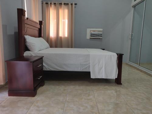 a bedroom with a bed with a wooden frame and a dresser at casa Verano in Cabarete