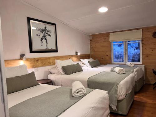 a bedroom with three beds in a room at Hain Casa Hotel in Punta Arenas