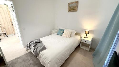 a white bedroom with a bed and a lamp on a table at Posada de María Casa Cori 5 in Talavera de la Reina
