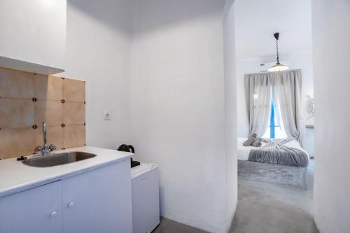 a white kitchen with a sink and a bed at Hotel Pleasure Blackbeach Santorini in Perissa