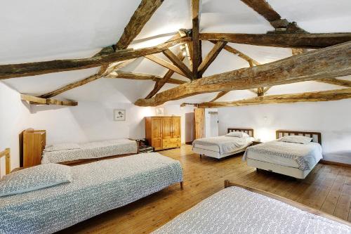 three beds in a room with wooden beams at Gîtes Du Logis De Bourseguin in Bourneau