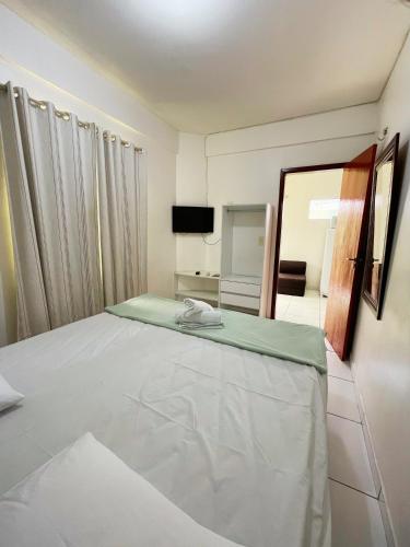 a bedroom with a large white bed with a mirror at Aldenora Flats in Fortaleza