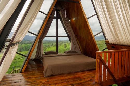 a bed in a room with a large window at Nimo Tea Resort in Tanara