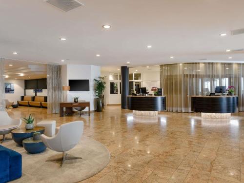 a lobby of a hotel with couches and chairs at Mövenpick Hotel Lausanne in Lausanne