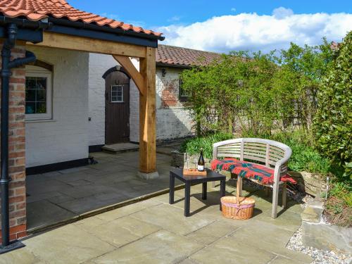 a patio with a bench and a table at Winship Cottage in Winestead