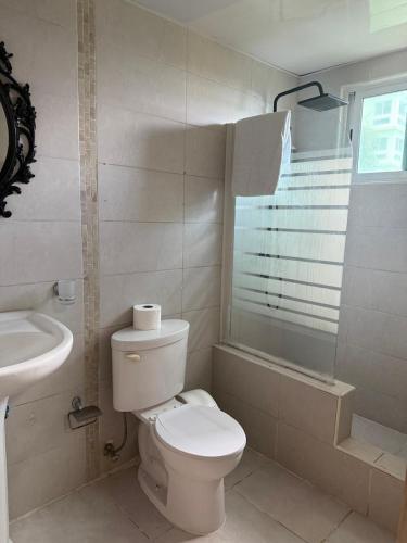 a white bathroom with a toilet and a sink at Vista al Caribe in La Francia