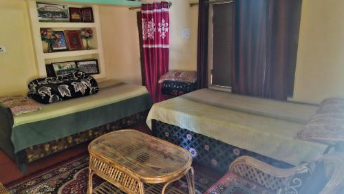 a room with two beds and a chair and a window at The Captain's Quarters in Ukhimath