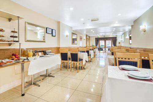 a dining room with tables and chairs in a restaurant at Best Western London Ilford Hotel in Ilford